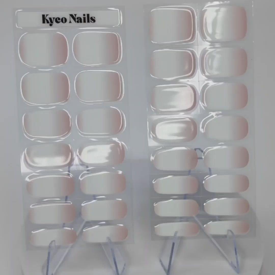 Close-up video showing Kyco Nails Luxe Creme semi-cured gel polish wraps out of their packaging, displaying the soft creamy nude shade and glossy gel finish.